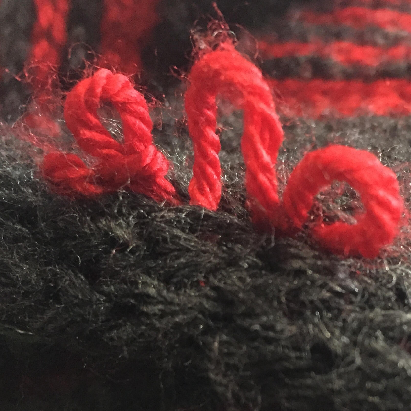 a macro shot of knitting, with red loops of yard sticking up